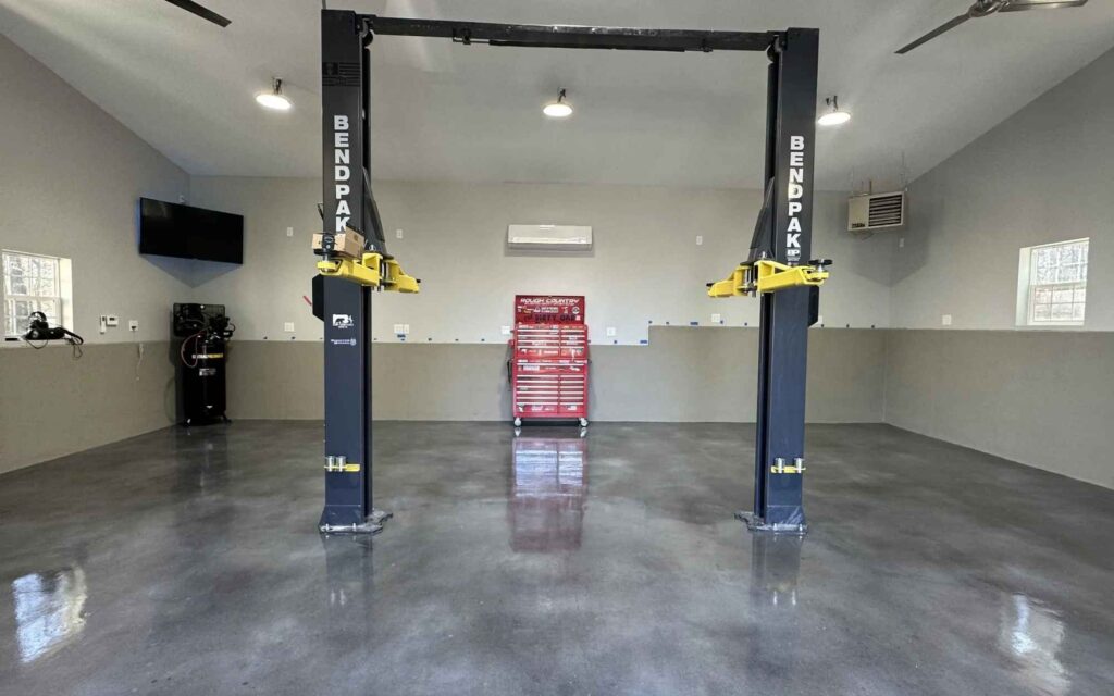 Spacious, modern garage with polished concrete floor, featuring a BendPak car lift and a red tool chest, creating a clean, efficient workspace ambiance.
